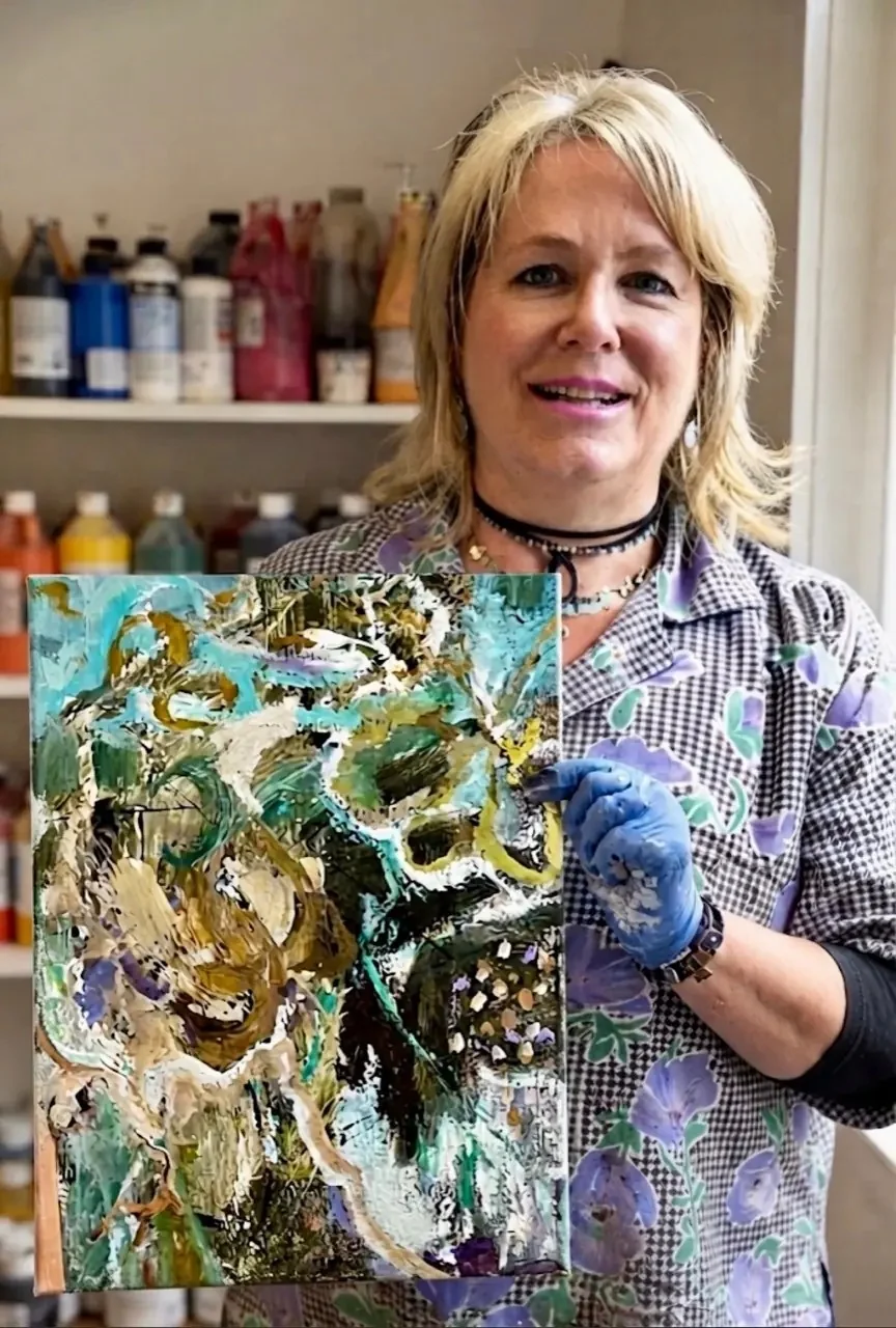 Renée Kanowitz in her Sydney studio holding a turquoise, olive and cream abstract painting